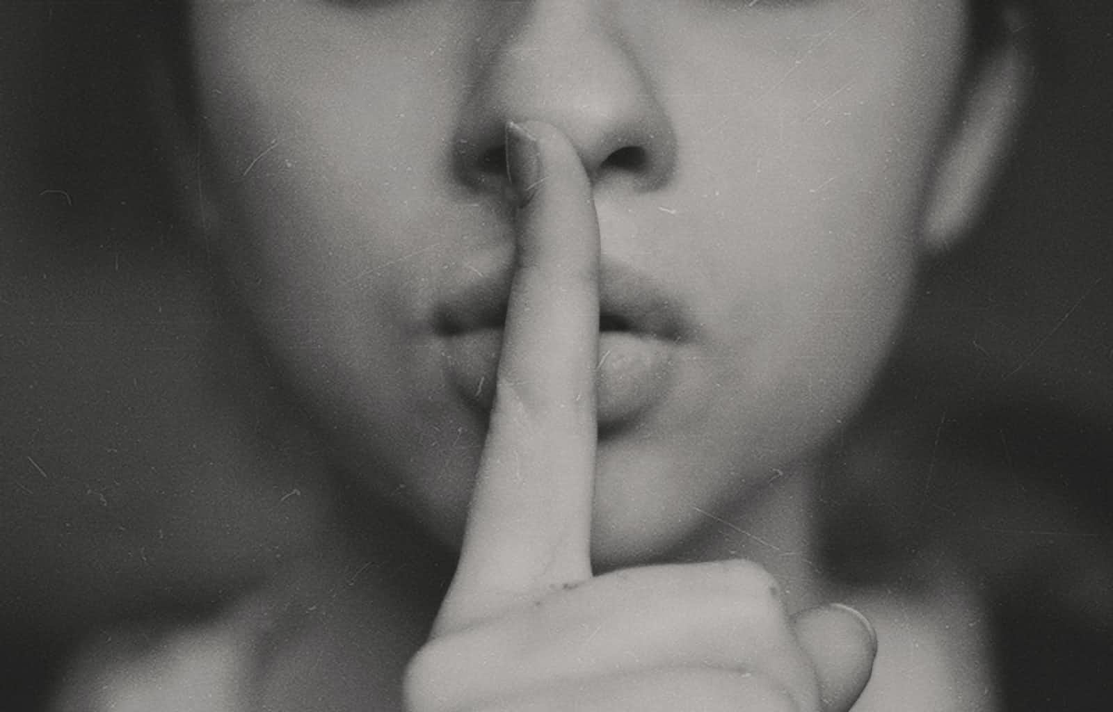 A woman placing her finger against her lips indicating to keep a secret