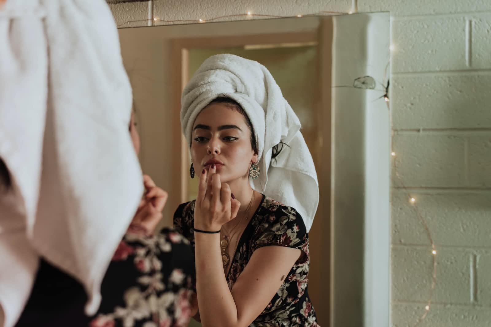A woman putting on makeup in front of a mirror