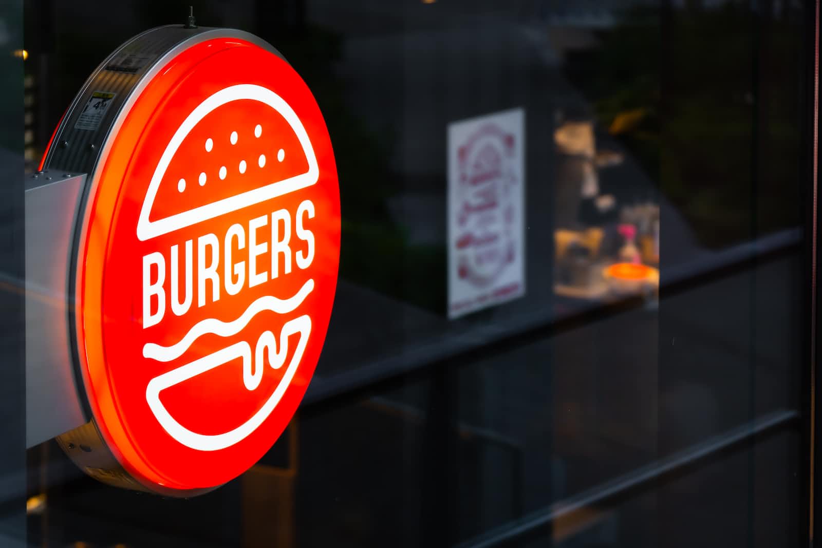 An illuminated red sign of a Burgers restaurant