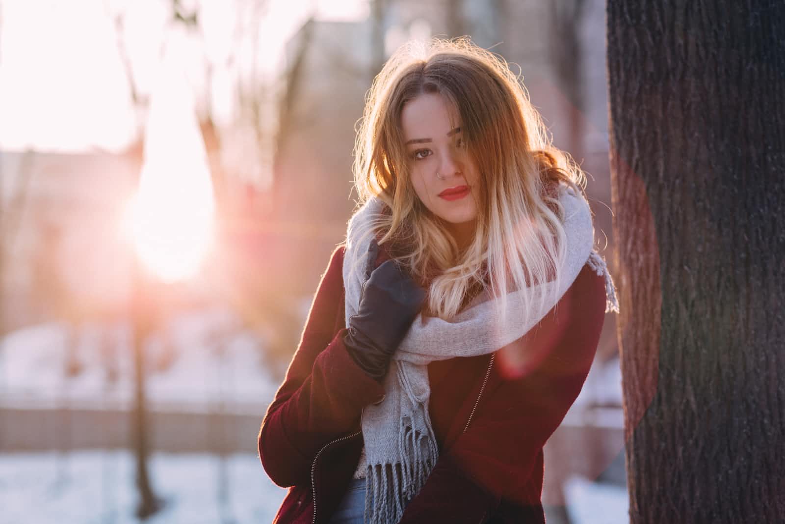 A woman with a white scraf and red coat at golden hour