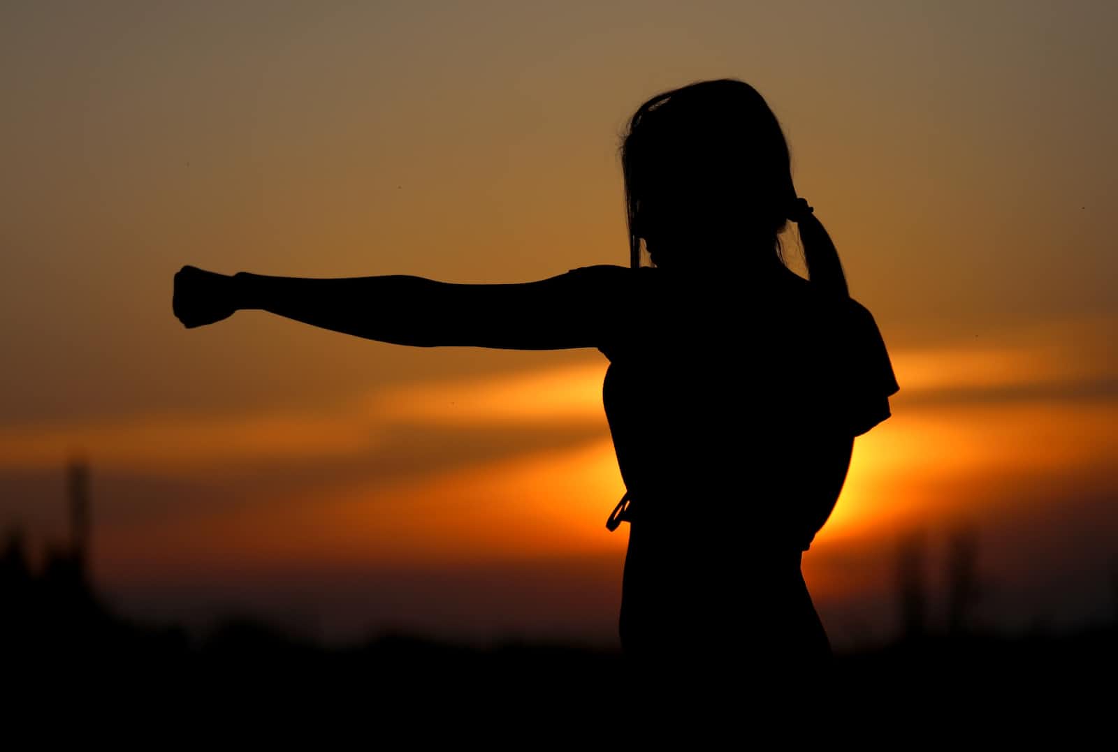 Shadow of woman practising kung fu at sunset