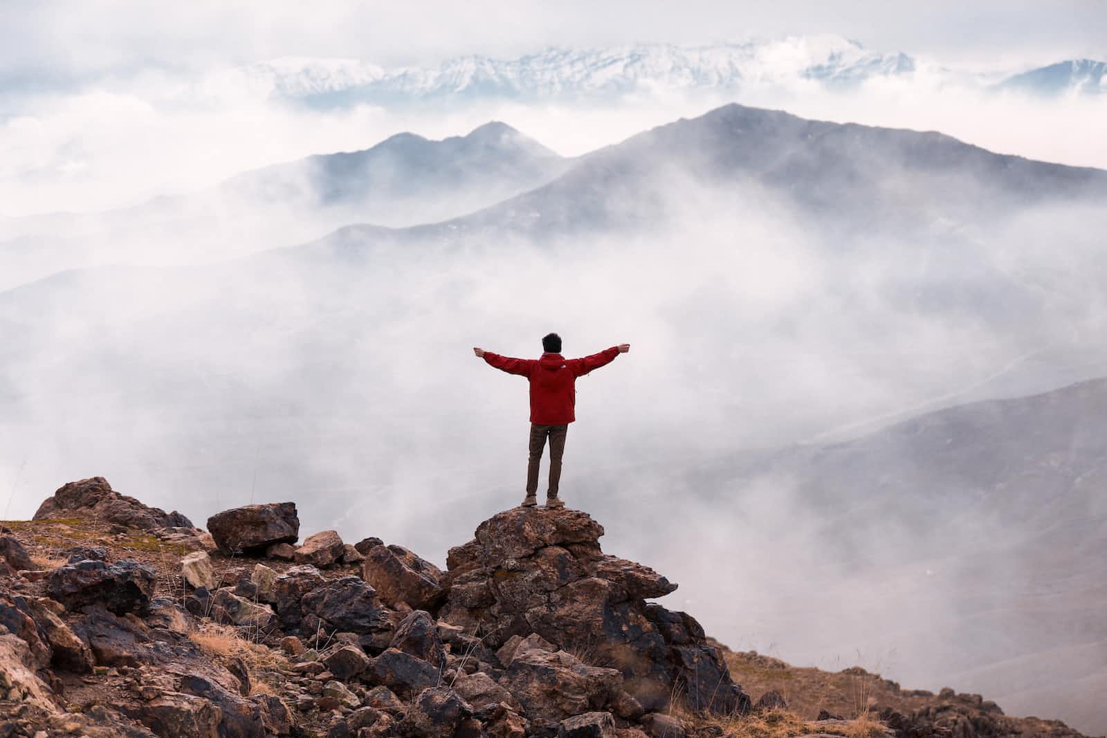 Jubilant and successful person with arms outstretched above a misty mountain range
