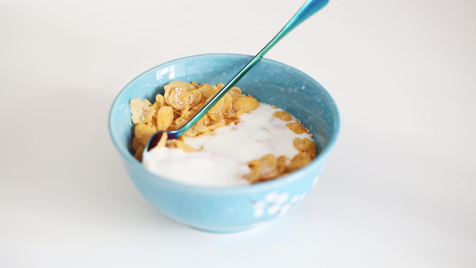 A bowl of cereal with milk and spoon