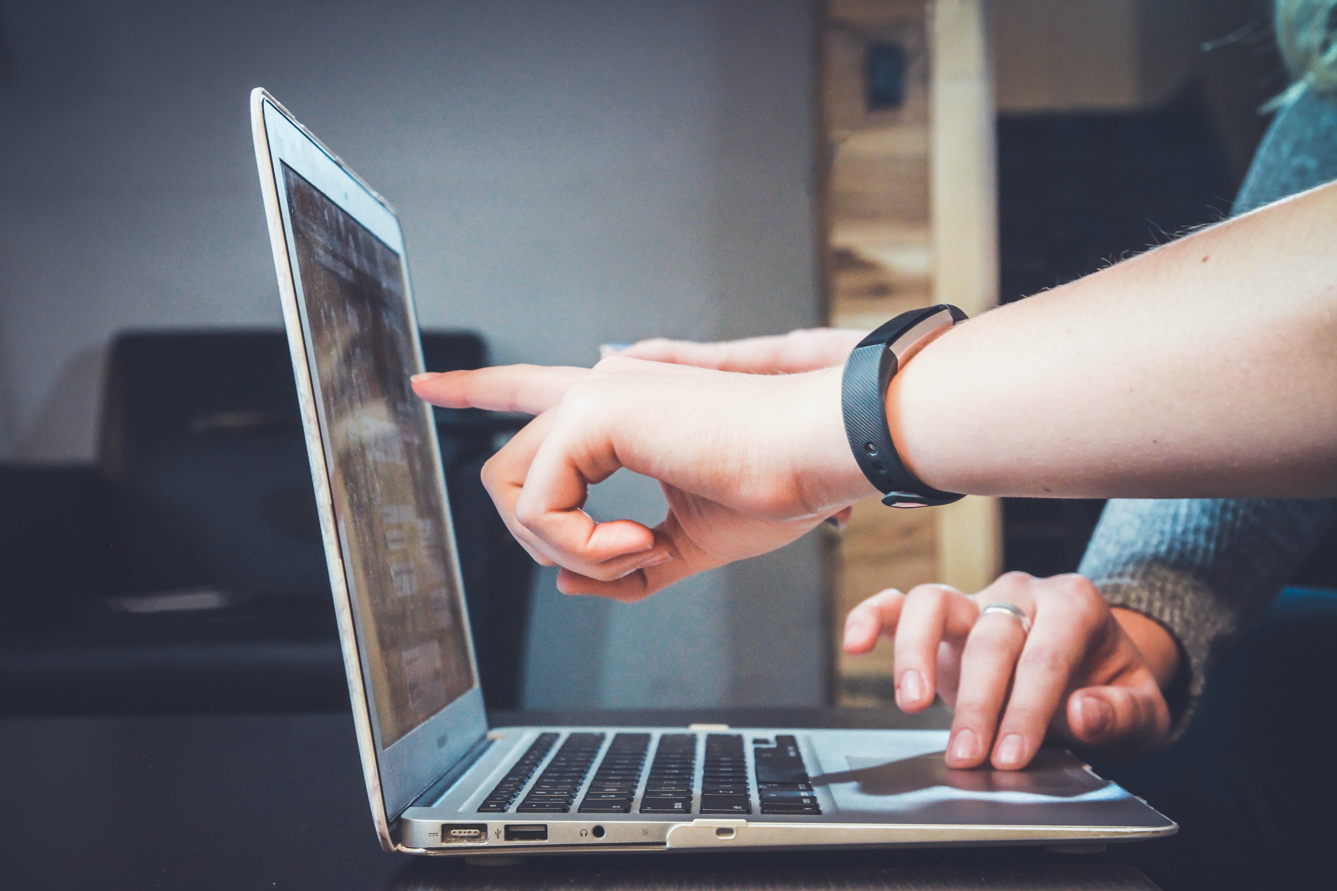 Two people pointing at something on a laptop screen