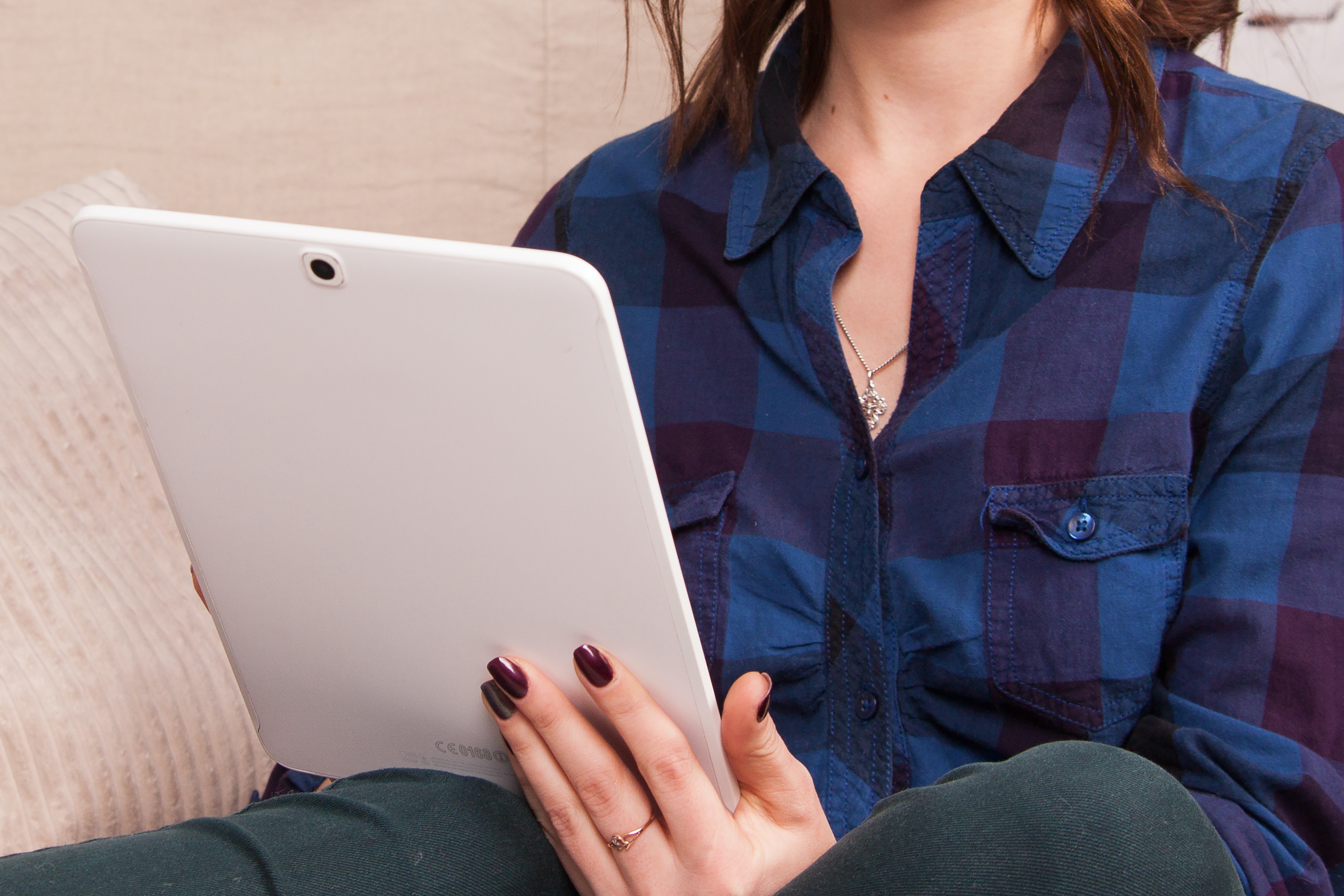 A woman in a buttoned blue shirt using a tablet computer